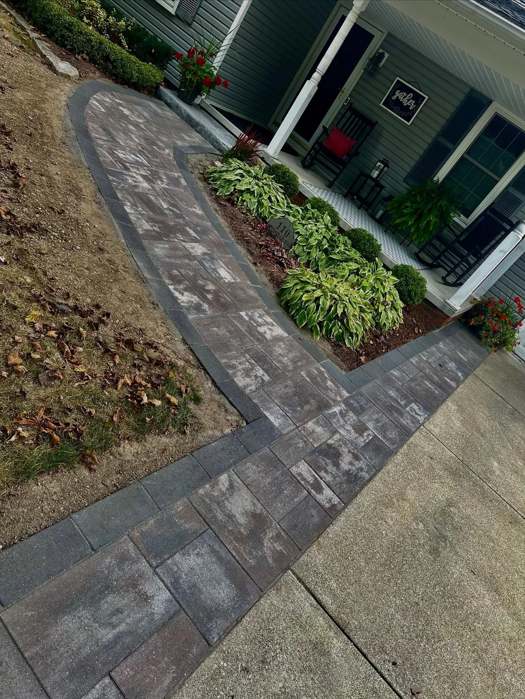 Curved paver walkway with planting bed leading to a covered front porch