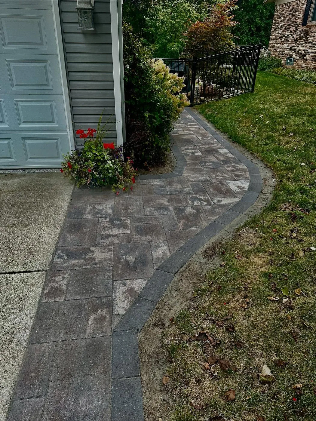 Herringbone paver walkway running from the driveway to a side gate